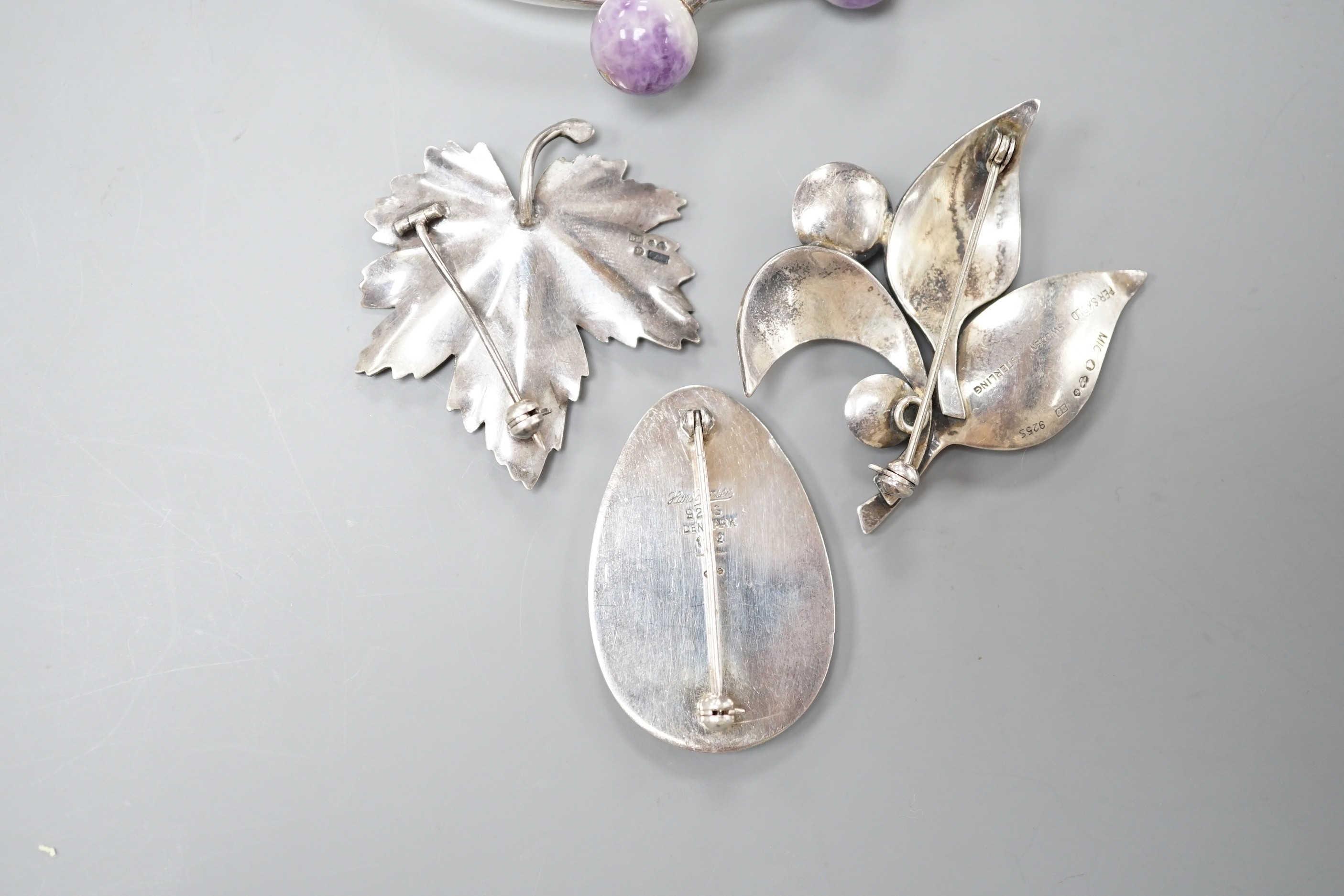 Four items of 20th century Scandinavian white metal jewellery, including a brooch and amethyst quartz set bangle by Hans Hansen and two Swedish white metal leaf brooches, bangle interior diameter 62mm.